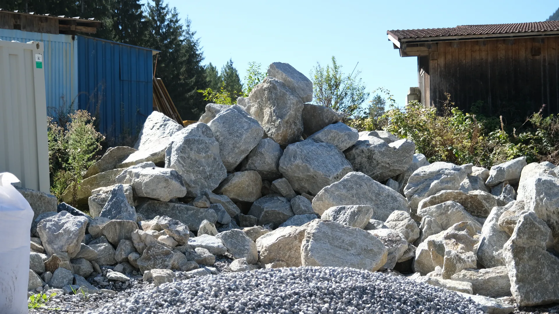 Große helle Natursteine, aufgeschichtet vor einem Holzstadel