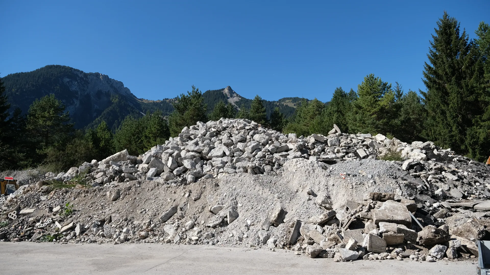 Haufen aus hellem Betonbruch vor Bergen