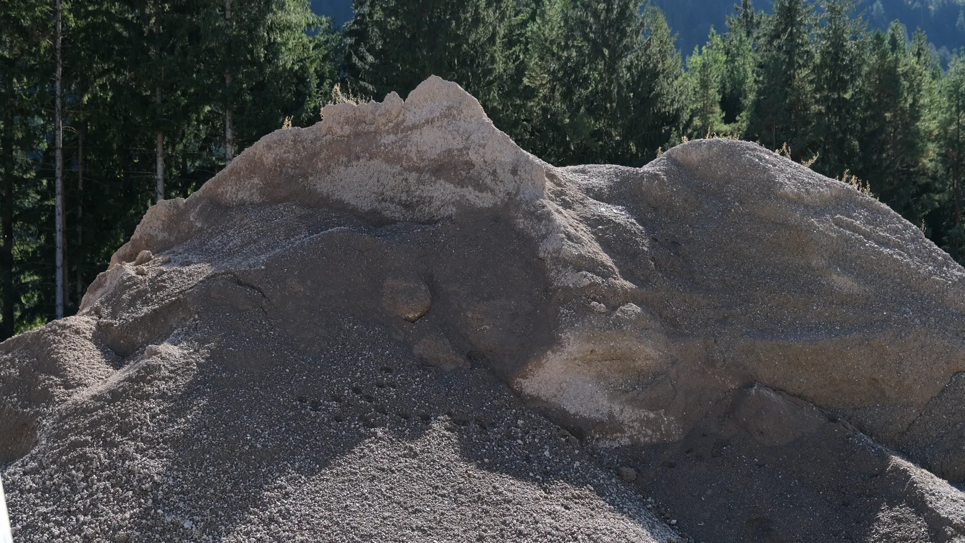 Haufen aus graubraunem Kies mit einzelnen größeren Steinen