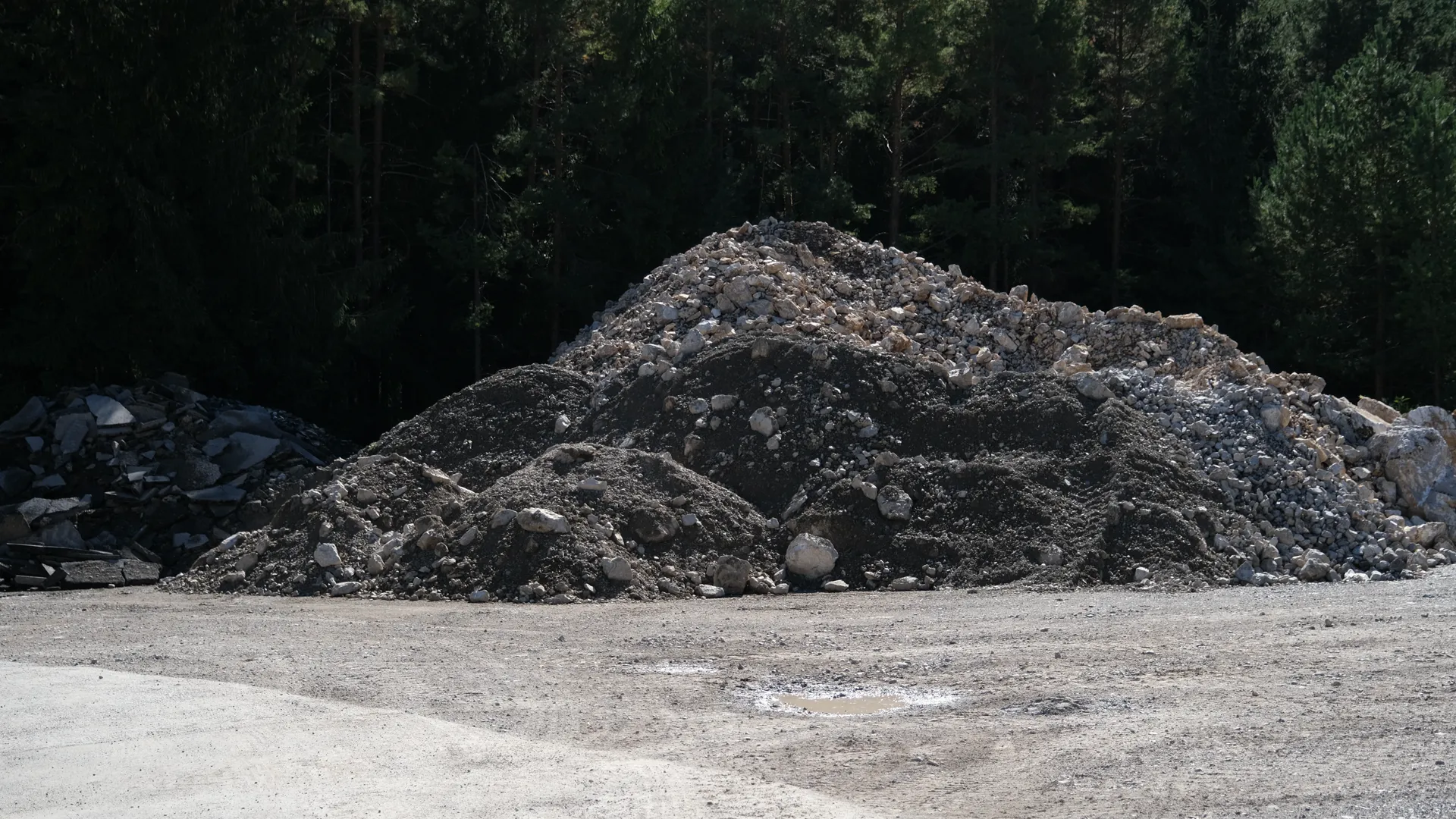 Flacher Haufen aus dunklem Material auf einem Schotterplatz
