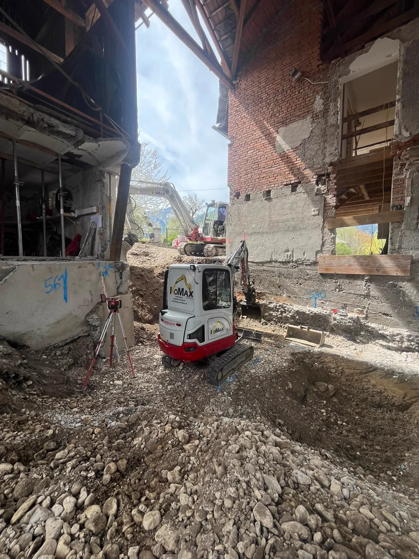Minibagger in einem teilweise abgebrochenen Altbau, ringsum Mauerreste und Schutt